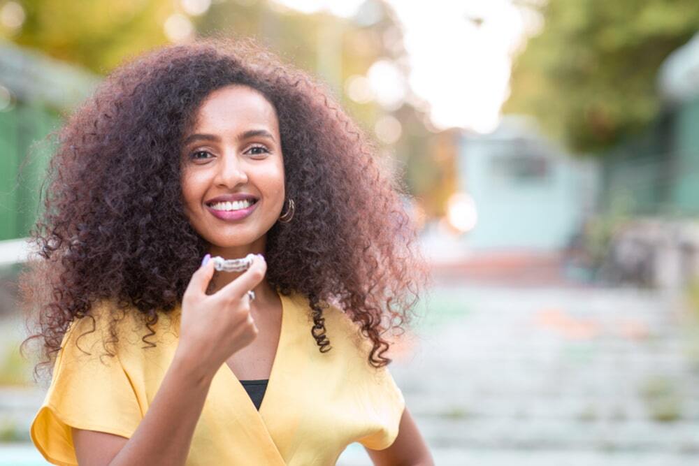 Beautiful smiling woman is holding Invisalign